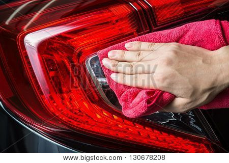 Car detailing series : Closeup of hand cleaning car taillights