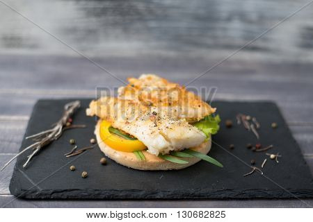 Fishburger with grilled fish pepper lettuce and herbs