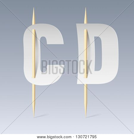 White paper cut font on toothpicks on grey background. C and D letters