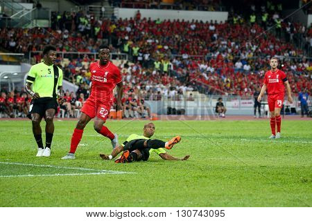 July 24, 2015- Shah Alam, Malaysia: Liverpool's Dovock Origi (red) watches a clearance by a Malaysian defender in a friendly match against Malaysia. Liverpool FC from England is on an Asia tour.