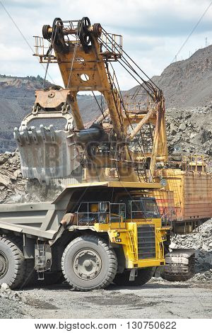 Excavator loading the iron ore to the cargo train on the opencast mining site