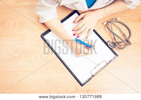 Medical prescription blank paper form for patients record with doctor's stethoscope & pen for writing on working table/ desk: Physician note on empty RX paperwork in hospital/ clinic office interio