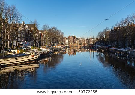 AMSTERDAM NETHERLANDS - 16TH FEBRUARY 2016: A view along the Waalseilandgracht Canal in Amsterdam at twilight. Building boats and reflections can be seen.
