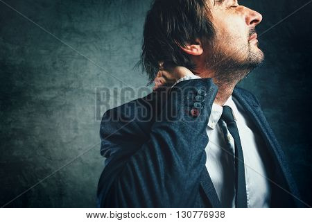Pain in the neck of a businessman stressed businessperson in elegant suit suffering from neckache.