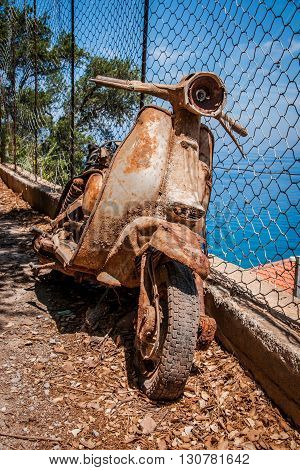 Rusty scooter by the fence on the sea coast