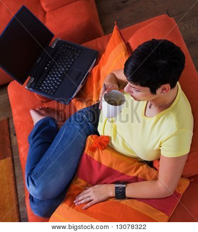 Junge Frau nutzt einen Laptop Computer ist ihr gemütliches Wohnzimmer.