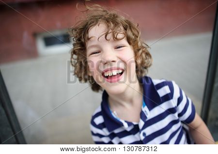 Skinny boy in a striped T-shirt laughing happily.