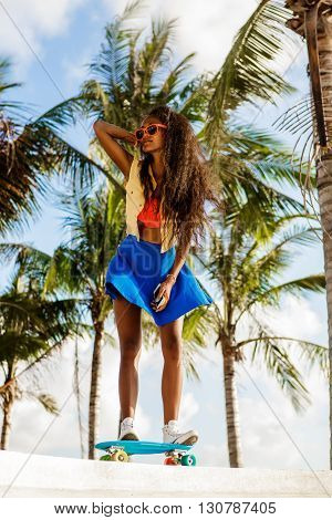 Beautiful Teenage Black Girl In Bright Outfit Rides At Tropical Skatepark.