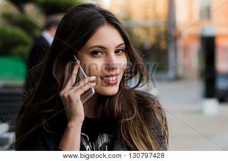 Woman phone talking. Closeup young happy beautiful smiling woman girl lady talking on mobile cell phone isolated cityscape outdoor street background. Positive face expression human emotion attitude