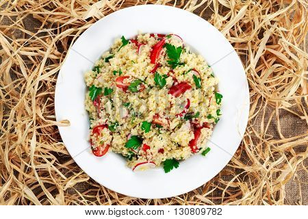 Homemade Fresh Couscous salad with vegetables, in plate on straw