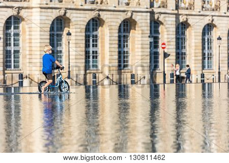 Children Having Fun In A Mirror Fountain In Bordeaux