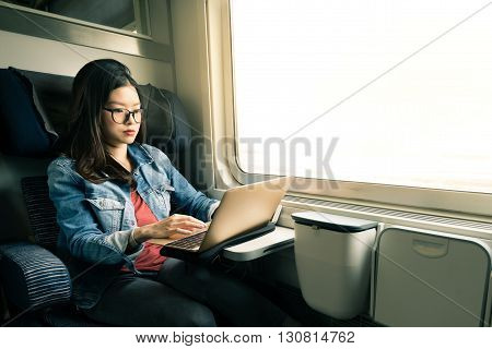 Asian woman work on laptop on train business travel concept warm light tone