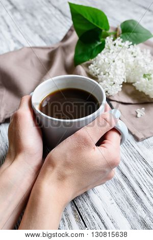 Coffee cup in female hands on a wooden table
