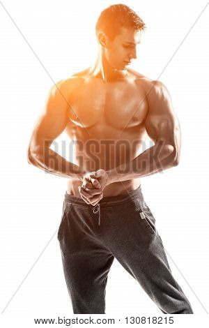 Strong bodybuilder man posing with perfect abs, houlders, biceps, triceps and chest. Isolated on white background Whith solar flare