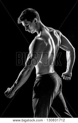 Strong bodybuilder man posing with perfect abs, houlders, biceps, triceps and chest on black background. Black and white