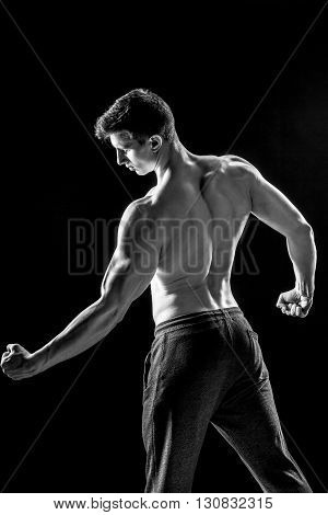 Strong bodybuilder man posing with perfect abs, houlders, biceps, triceps and chest on black background. Black and white
