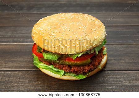 Classic american burger fast food. Big double burger at wood. Hamburger with fresh vegetables and meat. Burger with cheese, beef, tomato, lettuce. Cheeseburger at rustic wooden background.
