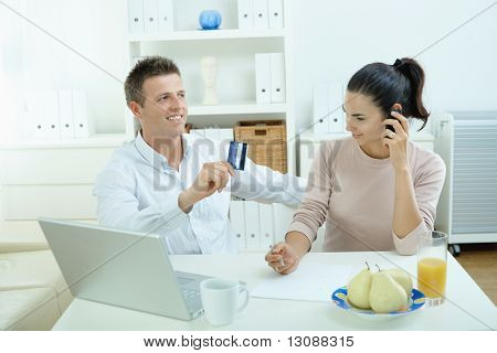 Mladý pár sedící u stolu, nakupování na internetu z domova. Volání telefon, pomocí laptopcomputer a
