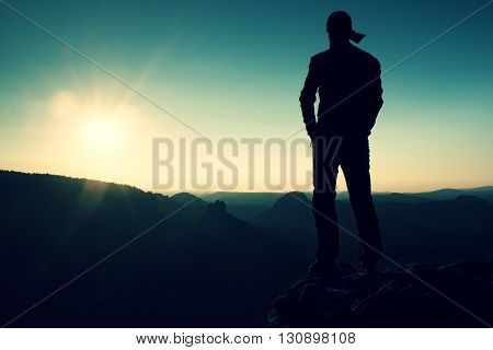 Hiker In Long Cap On Rock Empire And Watching To Sun. Beautiful Moment The Miracle Of Nature