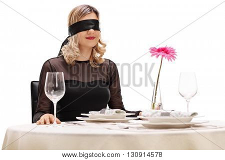 Young woman with blindfold on her eyes sitting at a romantic dinner on a blind date