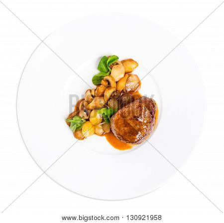Delicious beef steak in demiglas sauce with vegetable garnish. Isolated on a white background.
