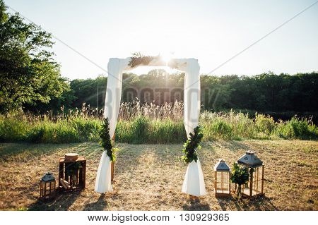 Wedding ceremony decoration in sunset. with wooden chairs