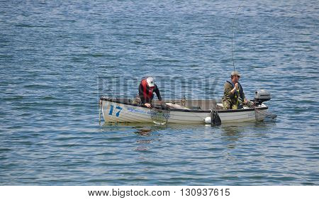 Grafham, Cambridgeshire, England - May 22, 2016: Two fisherman fishing with rods in boat.