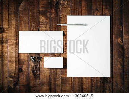 Blank stationery set on vintage wooden table background. ID template. Mockup for branding identity for designers. Blank letterhead business card envelope and pen. Top view.