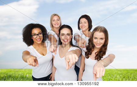 choice, friendship, body positive, gesture and people concept - group of happy different size women in white t-shirts pointing finger on you over blue sky and grass background