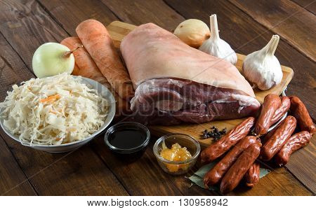 Raw pork knuckle onion, carrot, garlic, cloves, honey, soy sauce on wooden table