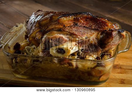 Roasted pork knuckle with braised sauerkraut with sausages on a wooden table