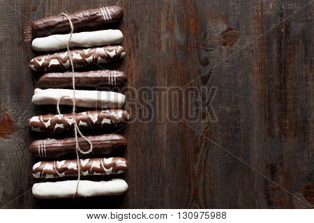 Chocolate cake sticks on dark wooden background. Black, white and decorated chocolate cake sticks. Flat lay. Sidepiece. Free space, void. Vertical line