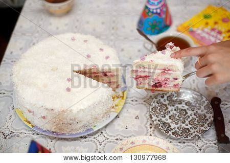 Cutting white strawberry cake with a knife