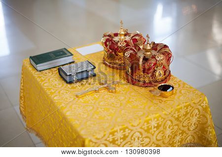 Orthodox Church wedding paraphernalia on table - cross, bible and crowns