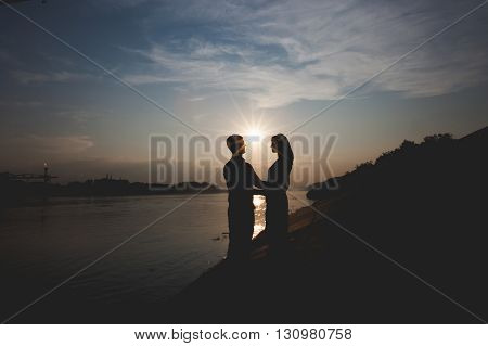 Romantic silhouettes of couple against the sunset sky