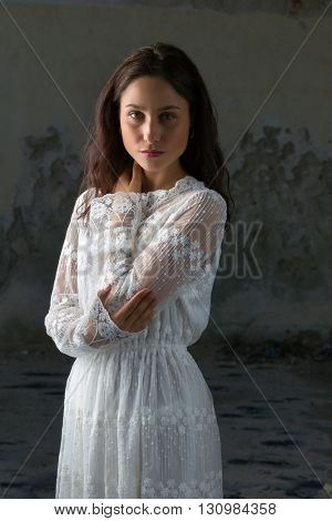 Antique edwardian lace dress worn by a beautiful woman against an old wall