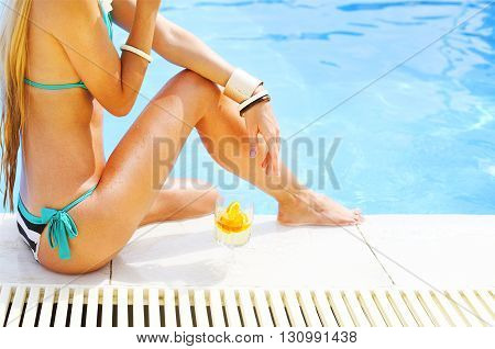 Pretty blond woman enjoying cocktail near the swimming pool. Close up