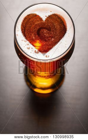 loving beer, heart symbol on foam in glass on black table, view from above