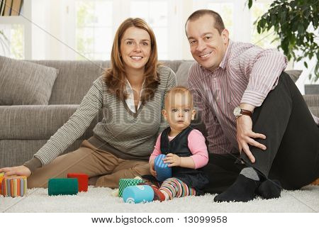 Mutlu bir aile bebek kız kameraya gülümseyen katta oturuyor.