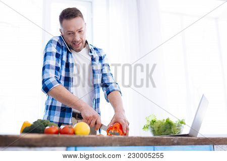Control Your Nutrition. Pleasant Nice Charming Man Making Call While Slicing Bell Pepper And Discuss