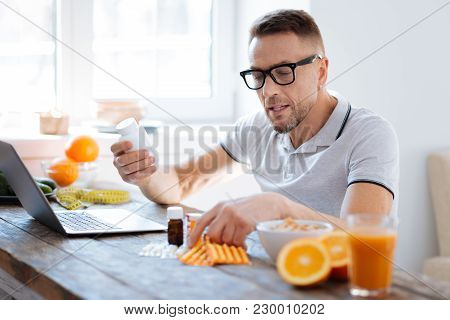 Biohacking For Beginners. Pleasant Reflective Worried Man Choosing Supplements For Biohacking And Ri