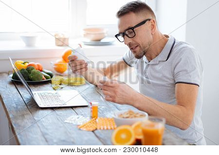 Nutritional Supplements. Pleasant Active Positive Man Scrutinizing Biohacking Supplements While Wear