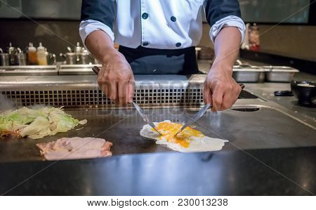 Hand Of Chef Cooking Egg On Hot Pan In Front Of Customers. Japanese Tepanyaki Steak