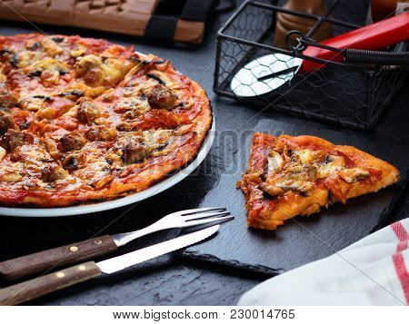 Homemade Pizza With Chorizo, Mushrooms, Mozzarella And Pieces Of Chipolata Sausages On Dark Table.