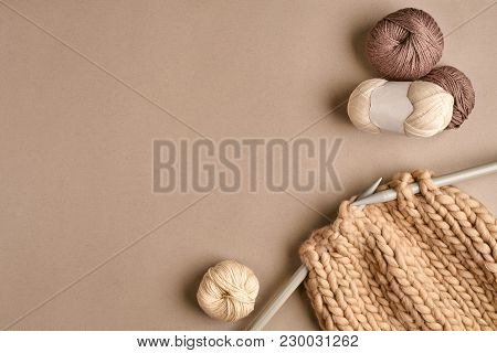 White And Brown Ball Wool And Knitting On Needles On Beige Background. Knitting As A Kind Of Needlew