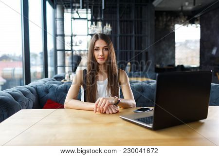 Young Woman Working On Her Laptop In The Restaurant. Smiling Beautiful Woman Smiling