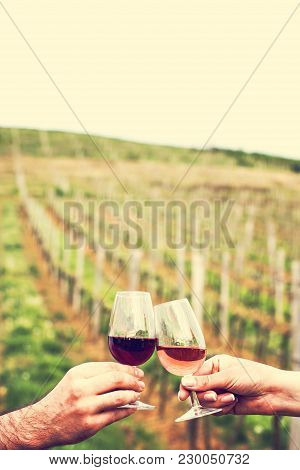 A Man And A Woman Check With Glasses Of Wine. Glasses With Red Wine In The Female And Male Hands. Wi