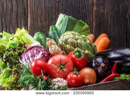 Fresh multi-colored vegetables in wooden crate. Wooden background.