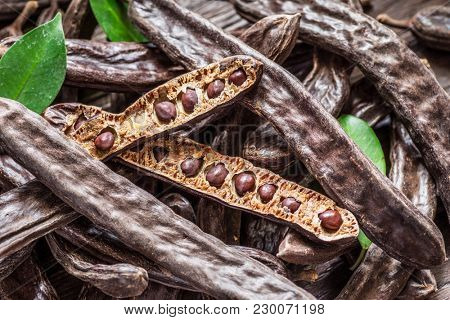 Carob pods and carob beans on the wooden table.
