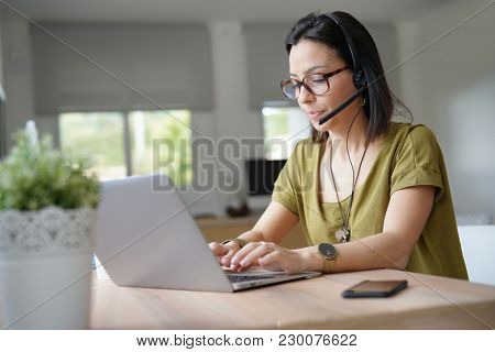 Teleoperator working in office with laptop and headset on